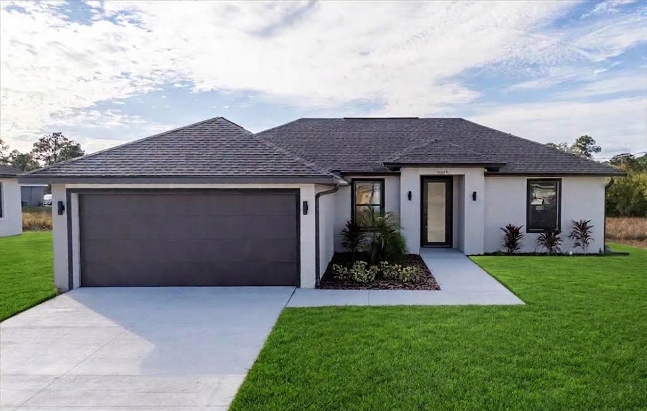 Front exterior elevation of the Martina model home featuring a modern single-family design, attached garage, concrete driveway, and landscaped yard in LaBelle, Florida by Paladium One.